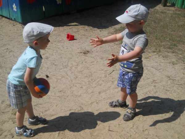 Два мальчика в кепках играют с мячом