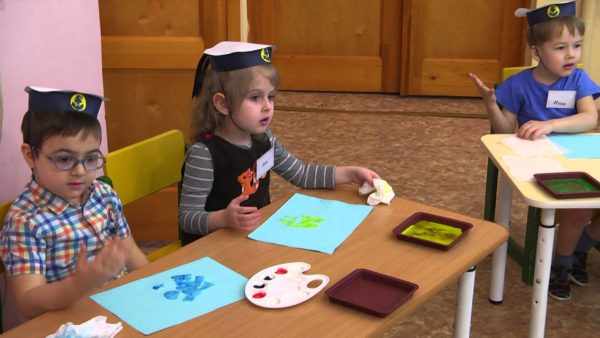 Трое детей в бескозырках за столиками рисуют