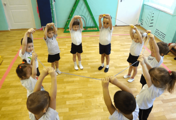 Дети стоят в кругу с поднятыми руками и держат верёвочку
