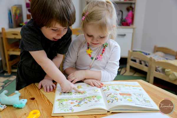 Мальчик и девочка рассматривают иллюстрации в книге