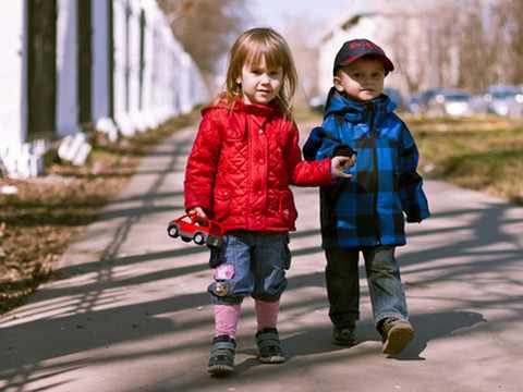 Мальчик и девочка в осенней одежде гуляют по улице