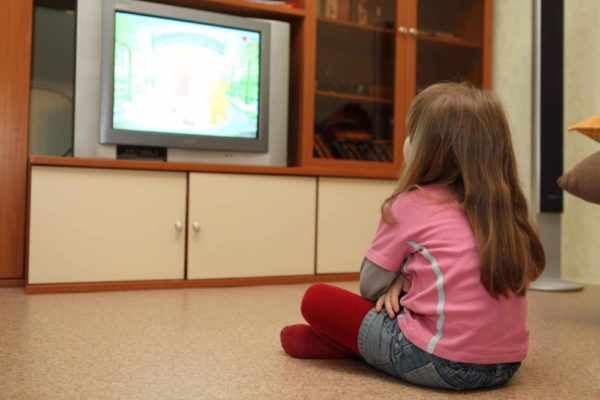Девочка смотрит мультфильм по телевизору