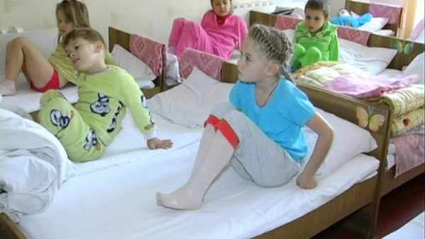 Дети в пижамах сидят в кроватках
