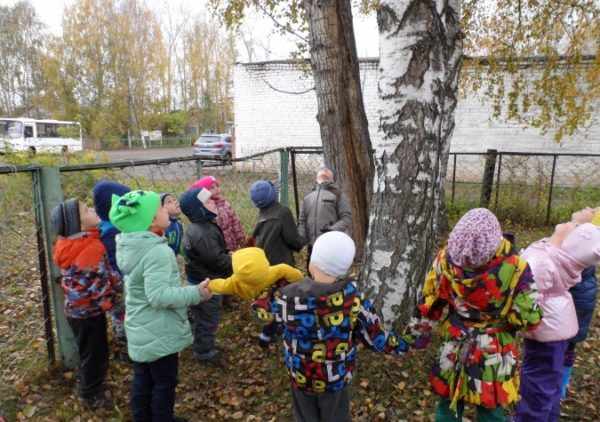 Дети, взявшись за руки, стоят вокруг дерева
