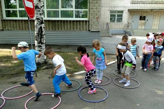 Дети на улице играют в подвижную игру с обучами
