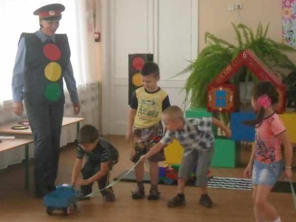 Дети играют с машинками в группе, рядом стоит педагог в форме полицейского