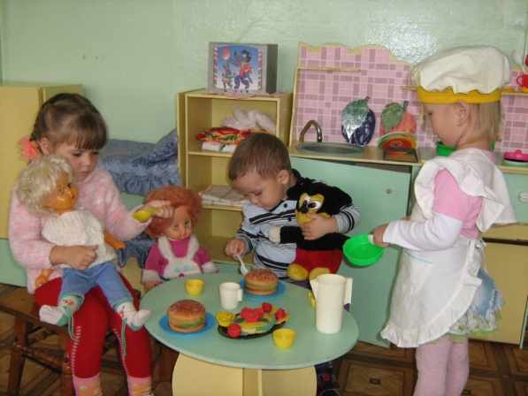 Две девочки и мальчик играют в чаепитие