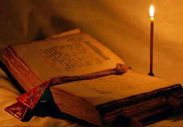 Открытая старинная книга и горящая свеча