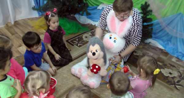 Воспитатель показывает детям игрушечного зайца и ёжика