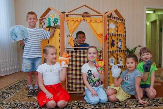 Четыре девочки и два мальчика с перчаточными куклами рядом с домиком-ширмой