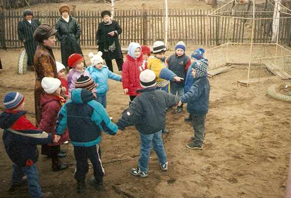 Дети в куртках и шапках стоят во дворе, взявшись за руки
