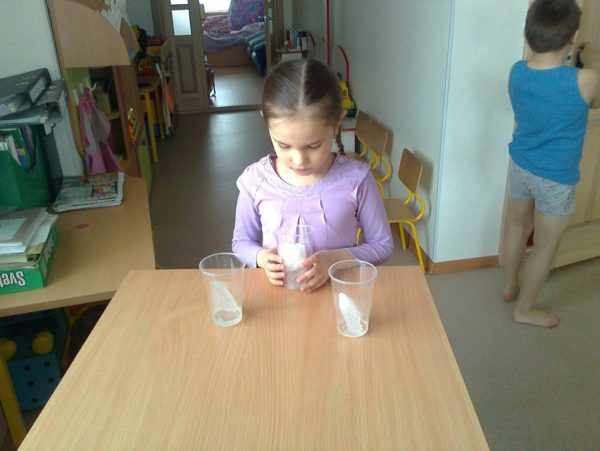 Девочка наблюдает за состоянием кусочков льда в пластиковых стаканах