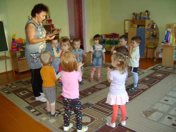 Дети, стоя в кругу, повторяют движения руками вслед за педагогом