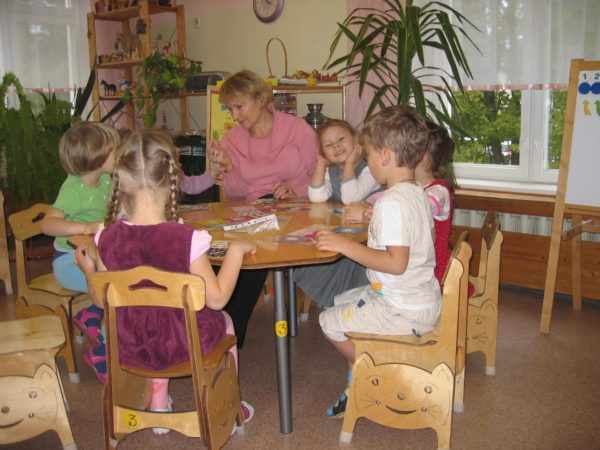 Дети и воспитатель сидят за столом, перед ними разложены дидактические материалы