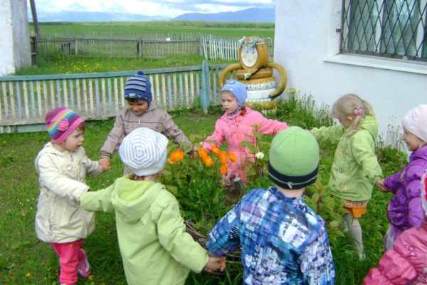 Дети водят хоровод вокруг клумбы с цветами