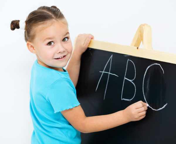 Девочка пишет английский алфавит мелом на доске