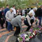 Люди в День Победы возлагают цветы к памятнику