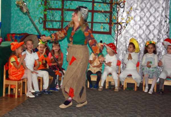 Воспитательница в костюме Бабы-Яги среди детей, одетых в костюмы лесных зверей и грибочков