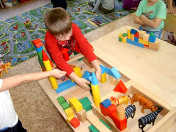 Дети строят зоопарк из деревянных фигурок