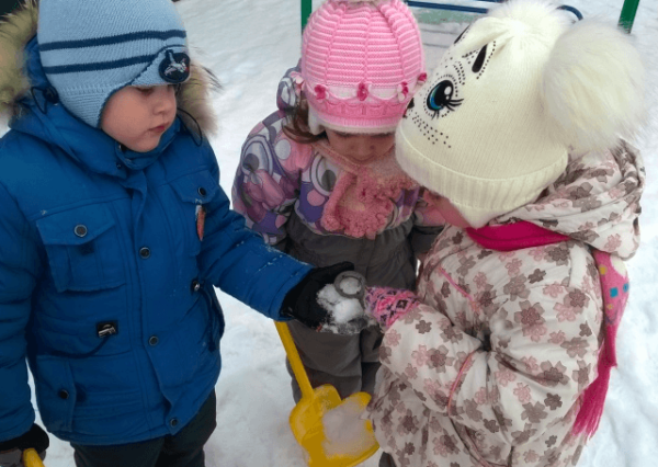 Трое детей рассматривают снег на прогулке