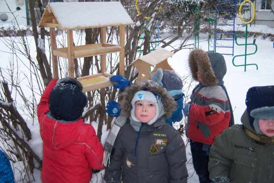Дети стоят на снегу возле скворечника