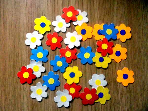 Разноцветные цветочки, сделанные из картона, лежат на столе