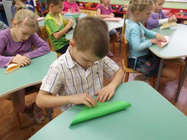 Дети, сидя за партами, занимаются конструированием из бумаги