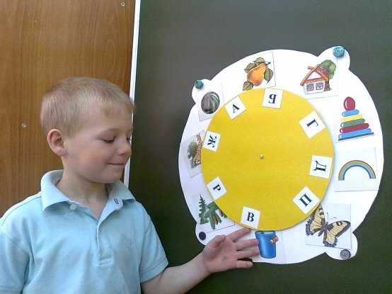 Мальчик на специальном макете соединяет изображения предметов с соответствующими буквами