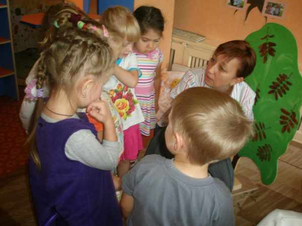 Воспитательница беседует с детьми, стоящими вокруг неё