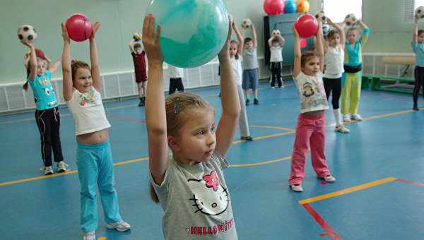 Дети выполняют упражнение с мячами в спортивном зале