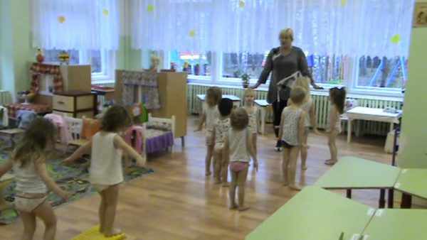 Воспитательница проводит гимнастику после сна с детьми, одетыми в трусы и майки