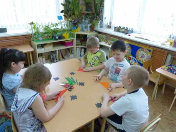 Дошкольники сидят за столом и складывают оригами из бумаги