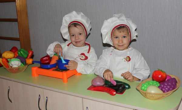 Две девочки в костюмах поваров готовят