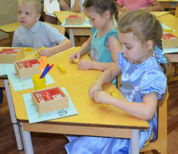 Дети сидят за столиком в детском саду, перед ними математические игрушки