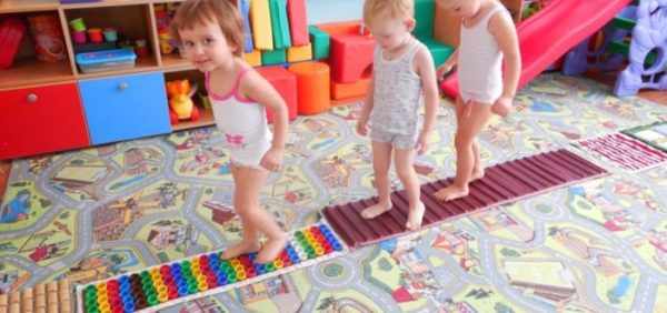 Дети идут по разноцветным массажным коврикам