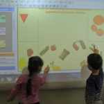 Два ребёнка распределяют предметы по группам на интерактивной доске