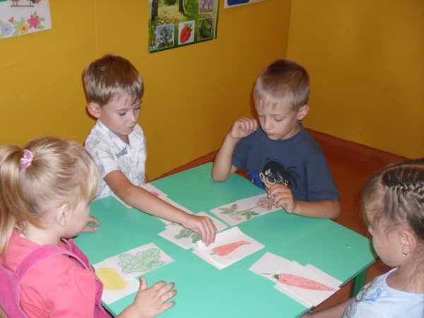 Четверо детей играют в игру «Вершки и корешки»