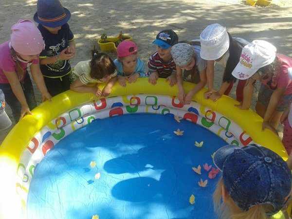 Дети рассматривают плавающие цветочки в надувном бассейне