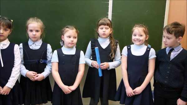Шестеро детей в школьной форме стоят у доски