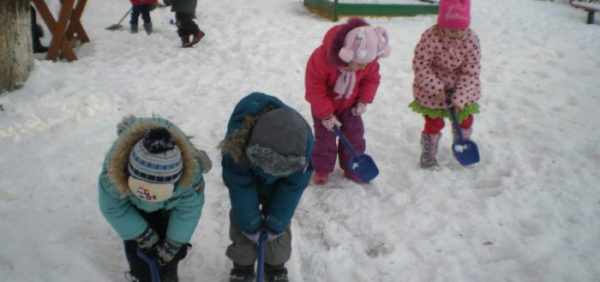 Четверо детей синими лопатками убирают снег
