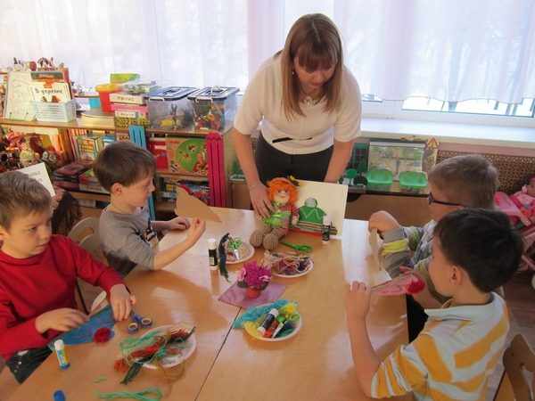 Воспитательница с игрушкой в руке объясняет детям задание