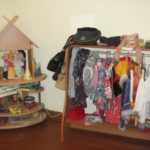Уголок ряжения: слева куклы на круглых деревянных полках с фанерной крышей, справа — стеллаж с перекладиной под вешалку для костюмов и покой сверху для шляп