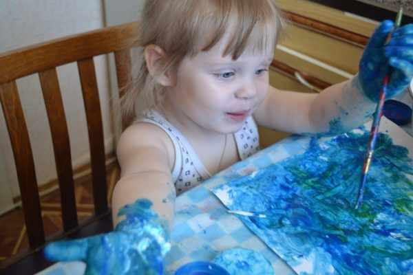 Девочка рисует синей краской