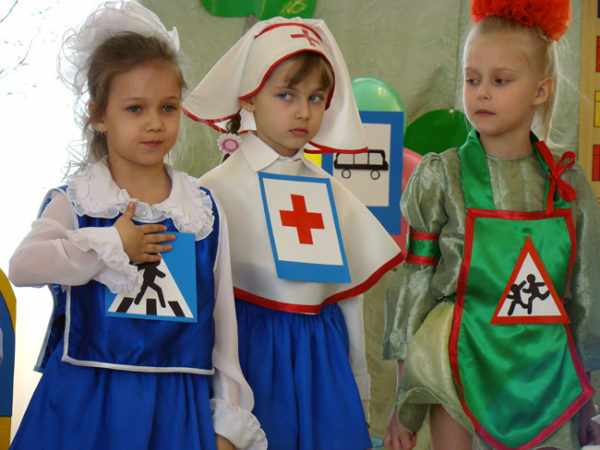Три девочки в костюмах со знаками дорожного движения на груди участвуют в представлении