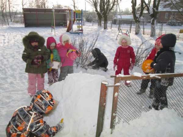 Дошкольники играют со снегом на прогулке