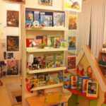 Стеллаж с книгами и игрушками, рядом размещены иллюстрации известных сказок