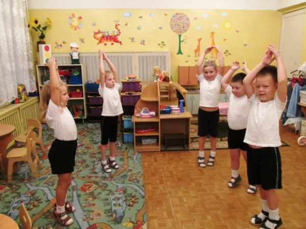 Дети в спортивной форме стоят с поднятыми вверх руками