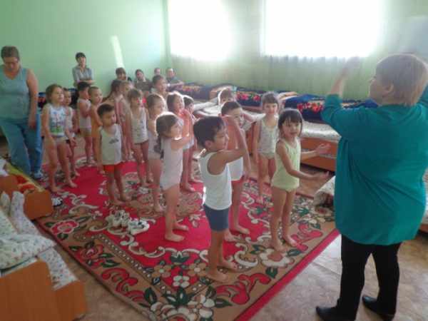 Воспитательница показывает движения, подняв руки вверх, дети стоя повторяют