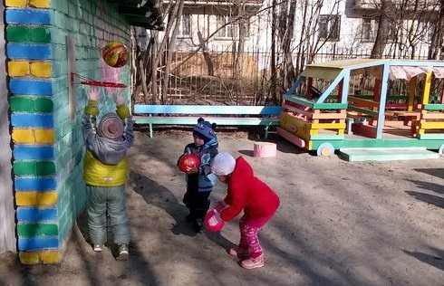 Дети на улице забрасывают мячи в баскетбольную корзину