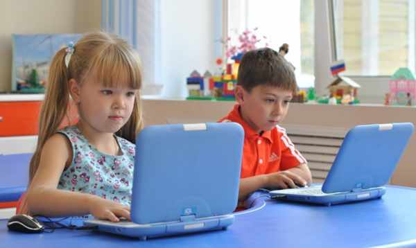 Девочка и мальчик сидят с голубыми лэптопами
